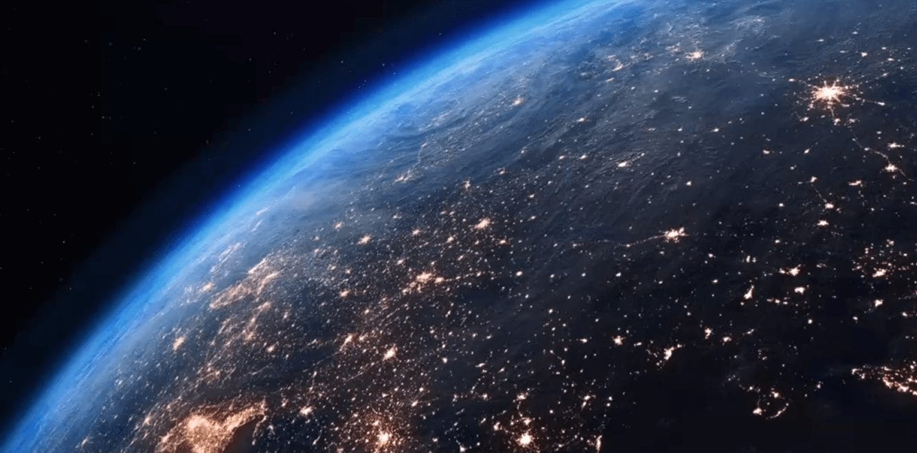 Satellite view of Earth at night with illuminated cities, symbolizing global trade