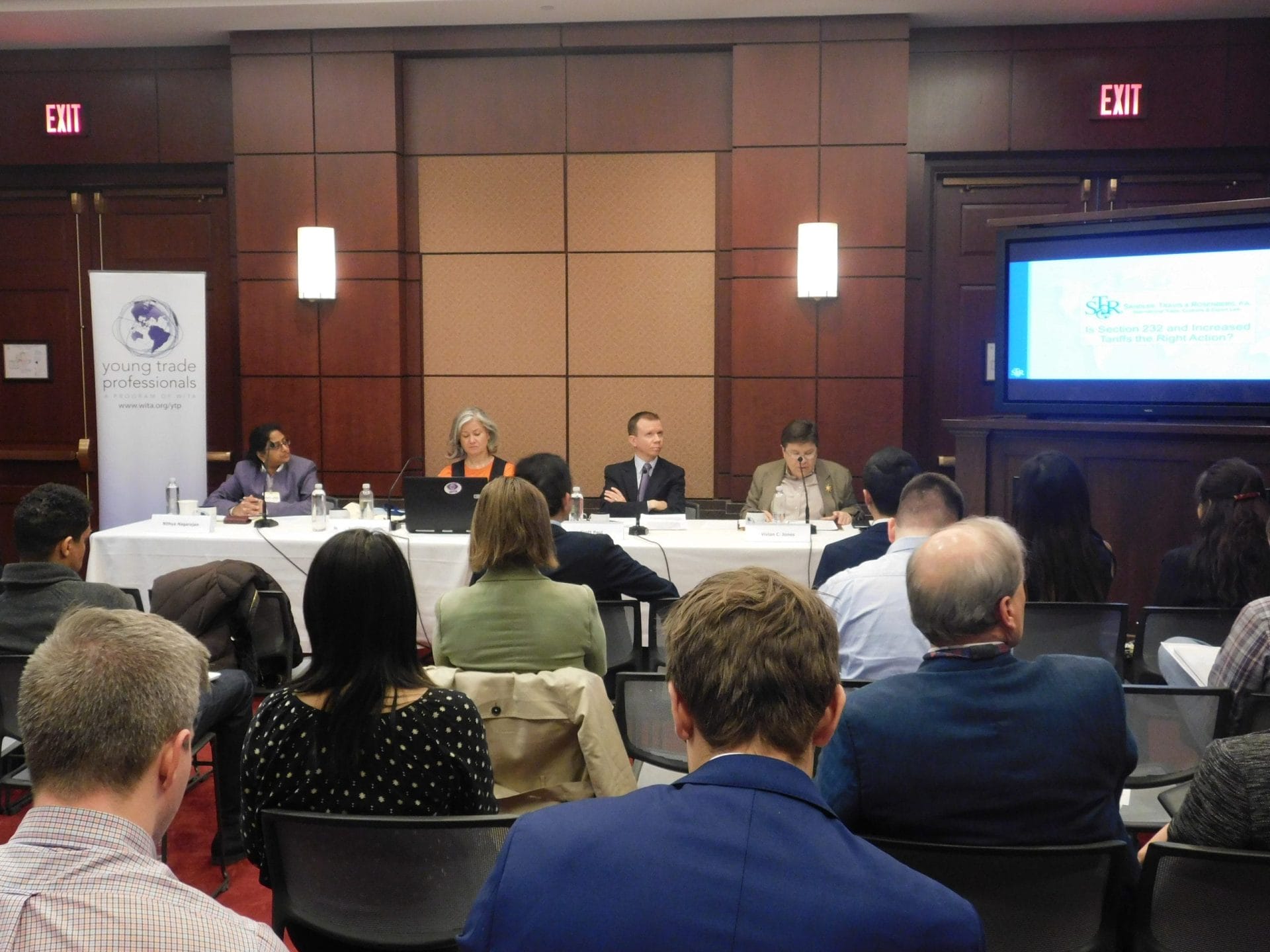 Panelists speaking at a WITA Young Trade Professionals panel discussion, with an audience seated in the foreground